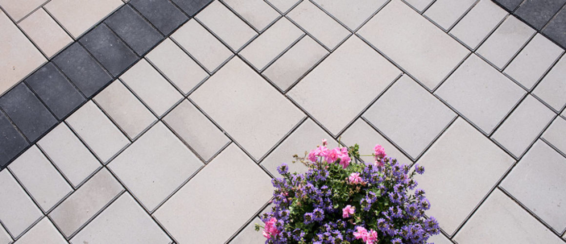 A photo of Highthorn pavers with pink and purple flowers on the surface. Highthorn has a black border